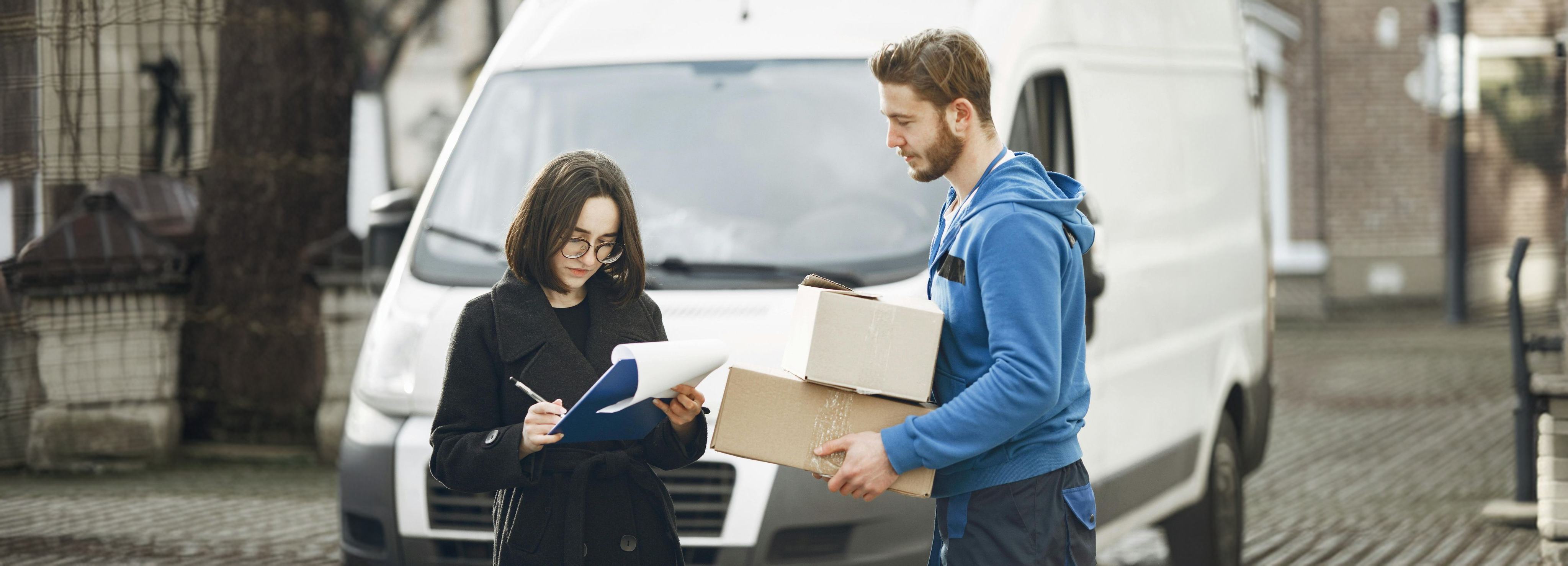 Courier handing parcels to a customer beside a delivery van