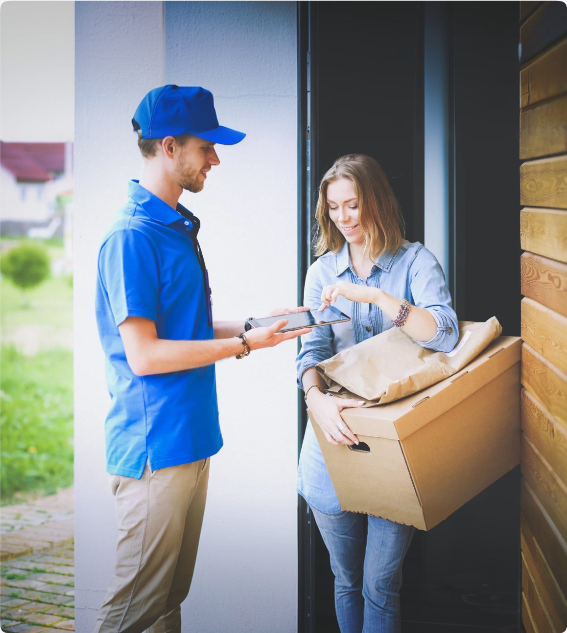 Friendly delivery driver handing parcel to customer at doorway