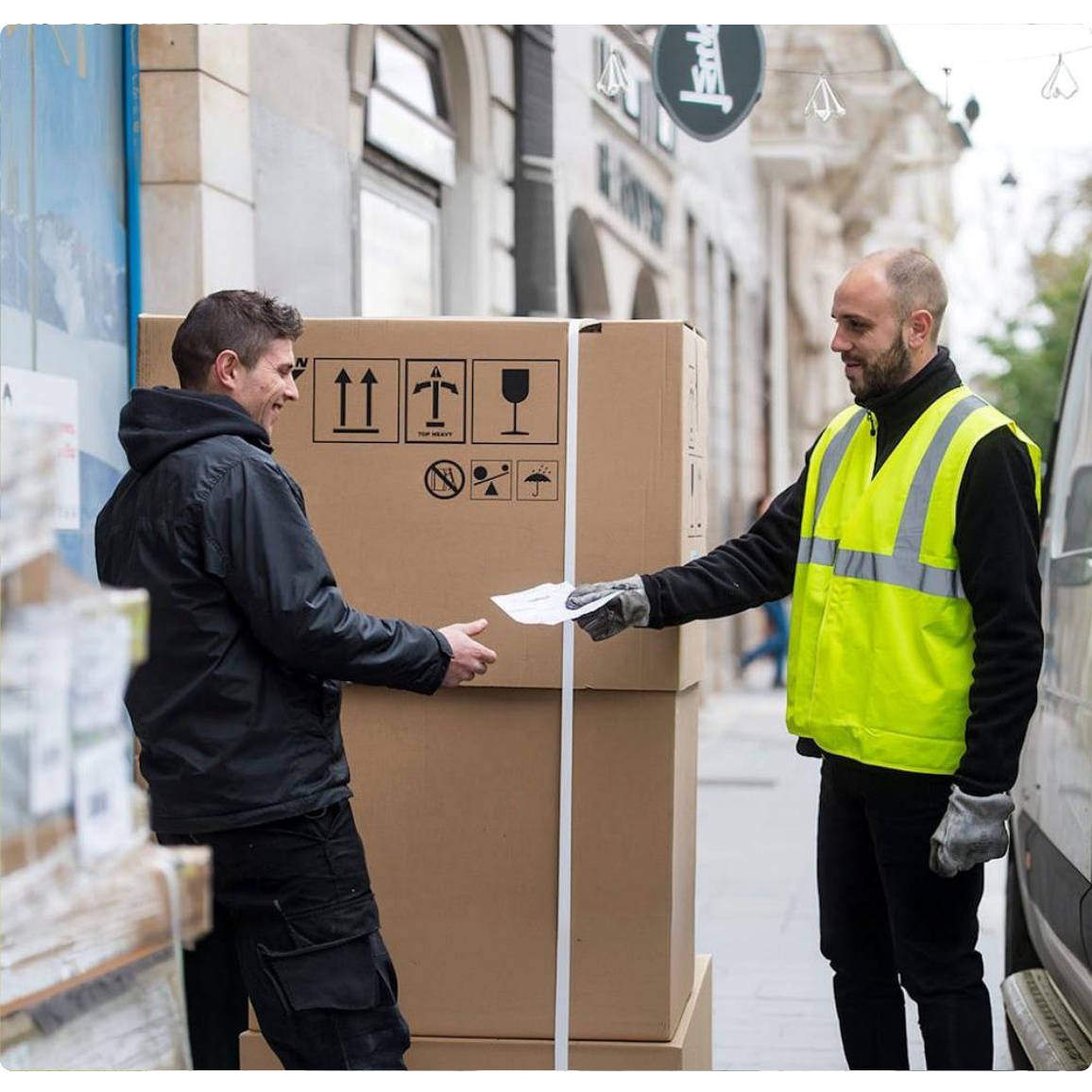 Two professional couriers carrying furniture out of a delivery van