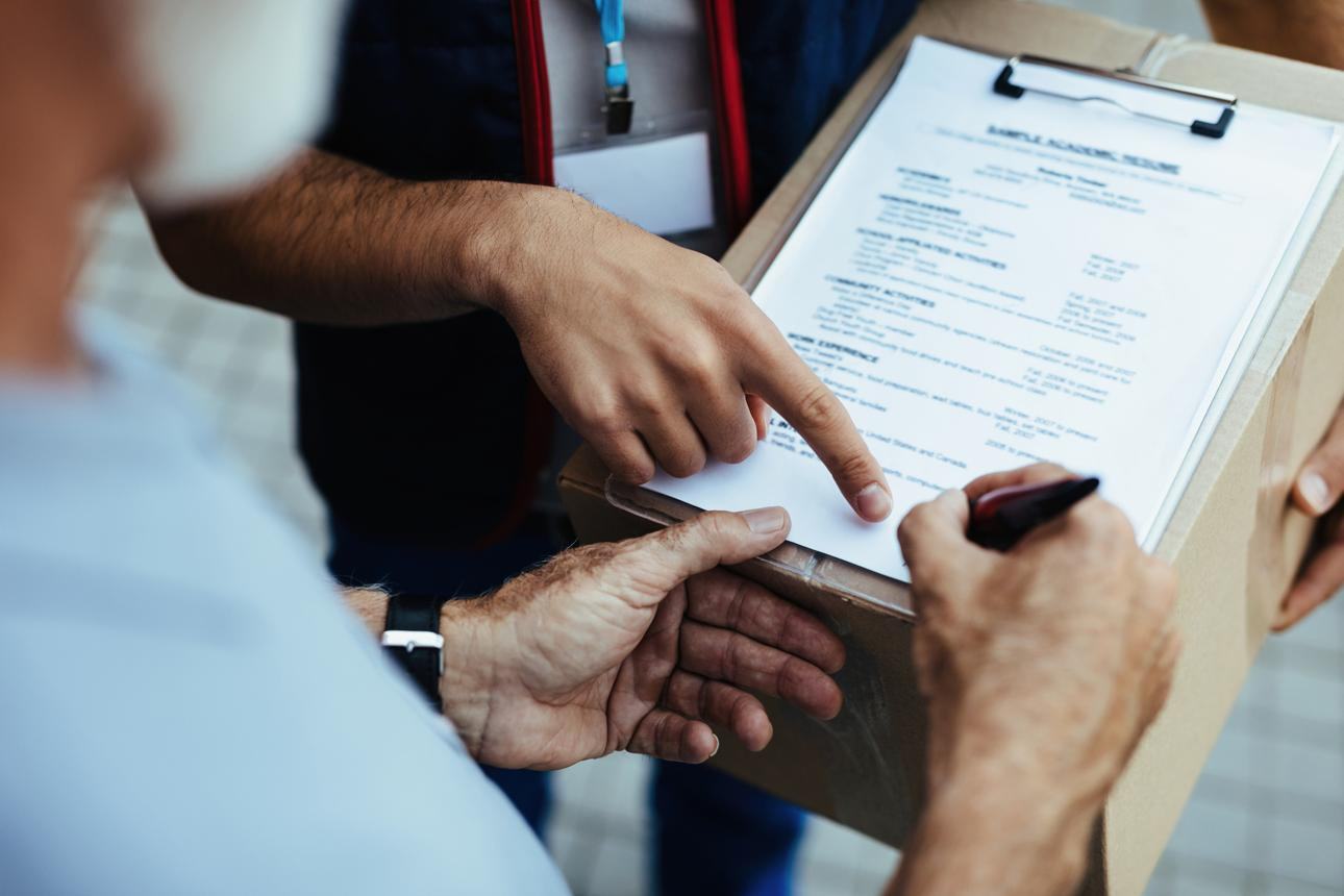 Customer signing delivery paperwork beside a courier